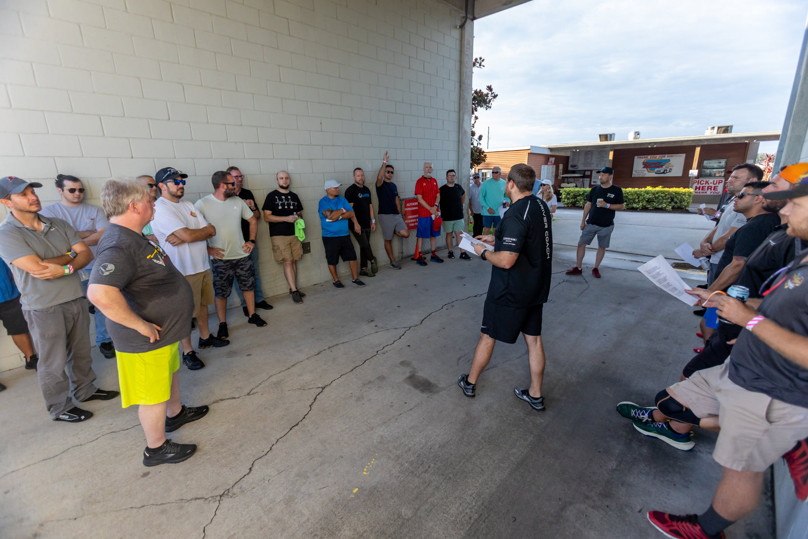 An Academy driver coach briefing a group of drivers before a track session