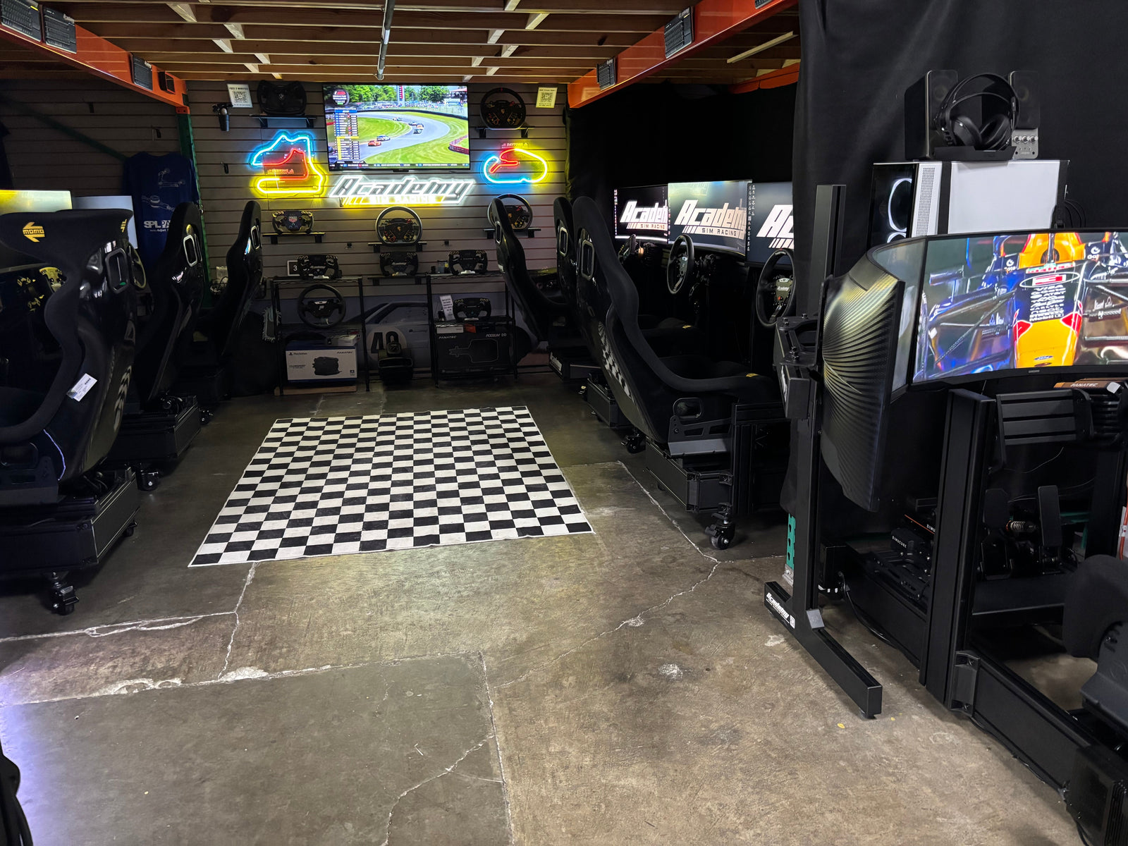 The Academy Sim Racing lounge in Tampa with several simulator rigs and a checkered floor
